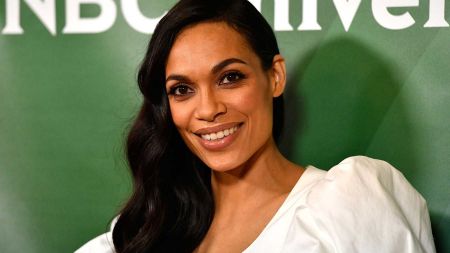 Rosario Dawson in a white dress poses for a picture.